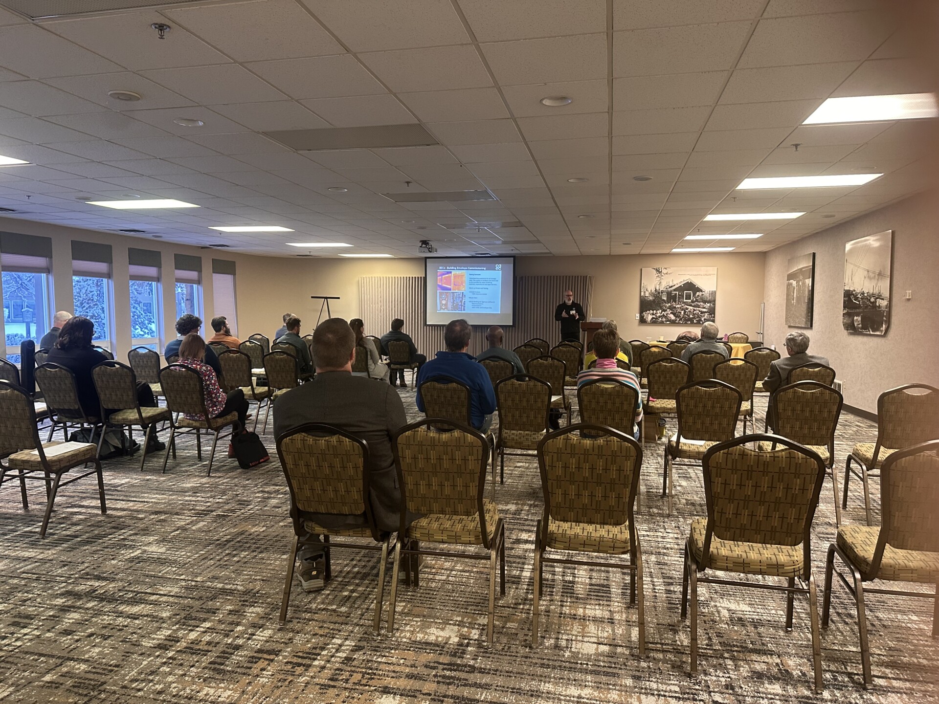 Spacious conference room with engaged presenter and attentive audience in a professional seminar setting.