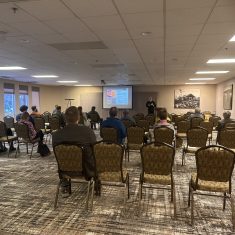Spacious conference room with engaged presenter and attentive audience in a professional seminar setting.