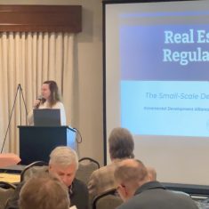 Young woman presents on real estate regulations at a professional seminar, engaging a focused audience.