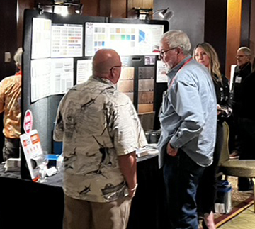 Engaged professionals explore colorful design materials at a vibrant trade show booth.