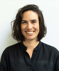 Smiling woman in casual attire radiating warmth and confidence against a light background.