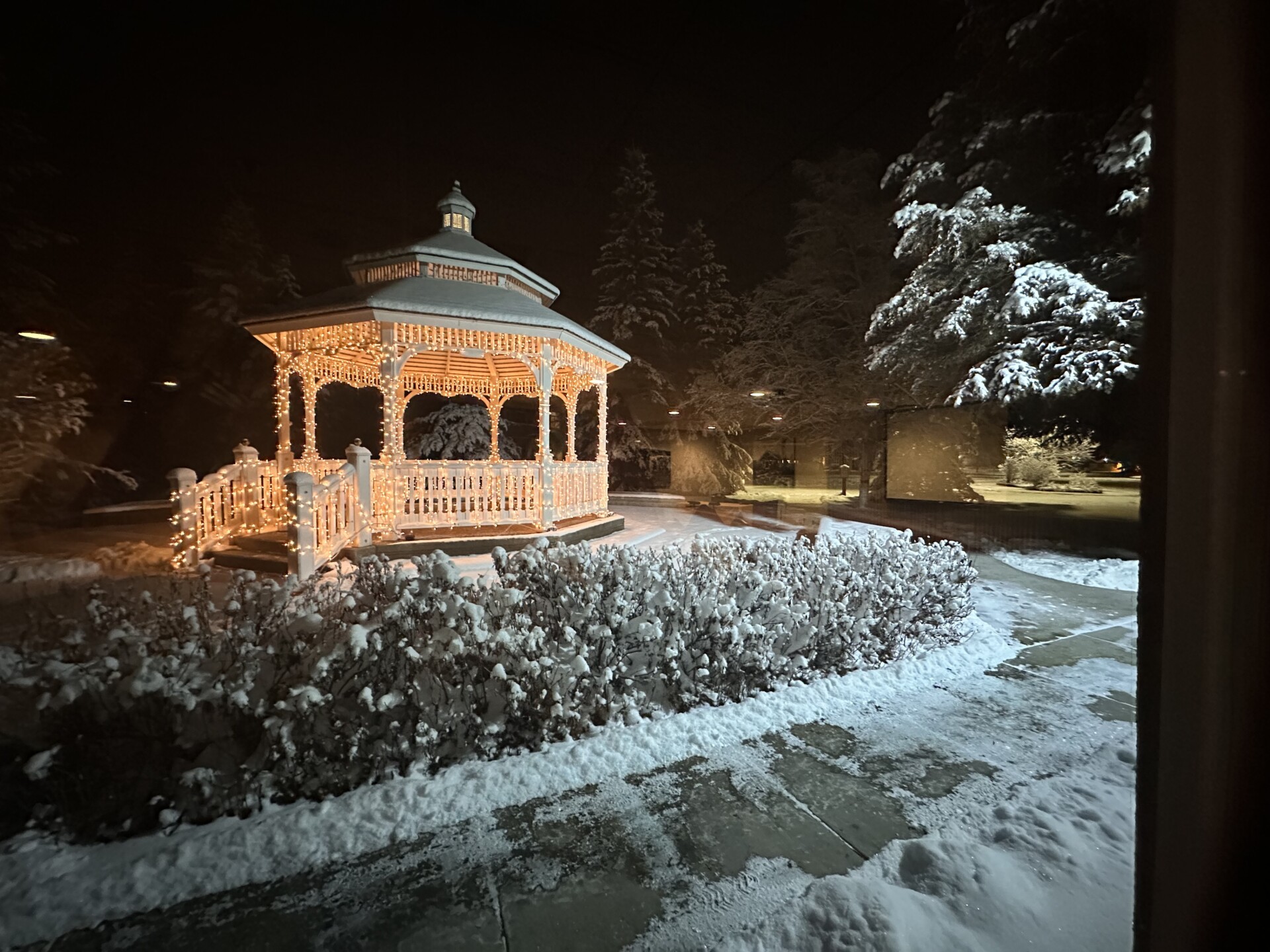 Winter gazebo illuminated with lights, surrounded by snow—a serene nighttime winter wonderland.