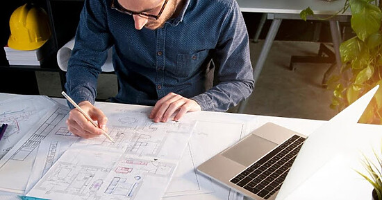 Young architect focused on architectural blueprints and design plans in a creative workspace.